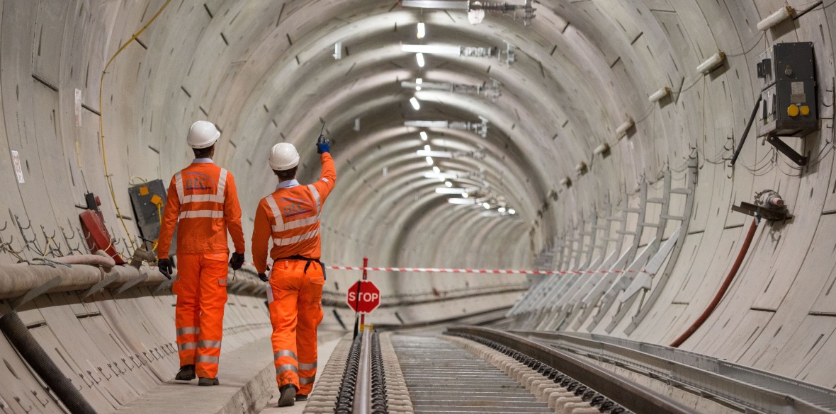 Two workers walk through a Crossrail tunnel in London
