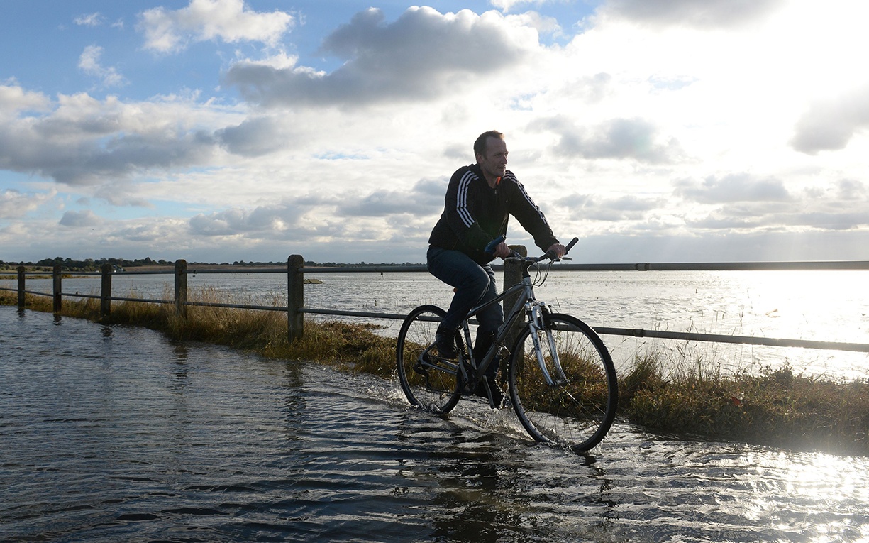 A man rides his bicycle on the crossing between Mersea Island and mainland Essex