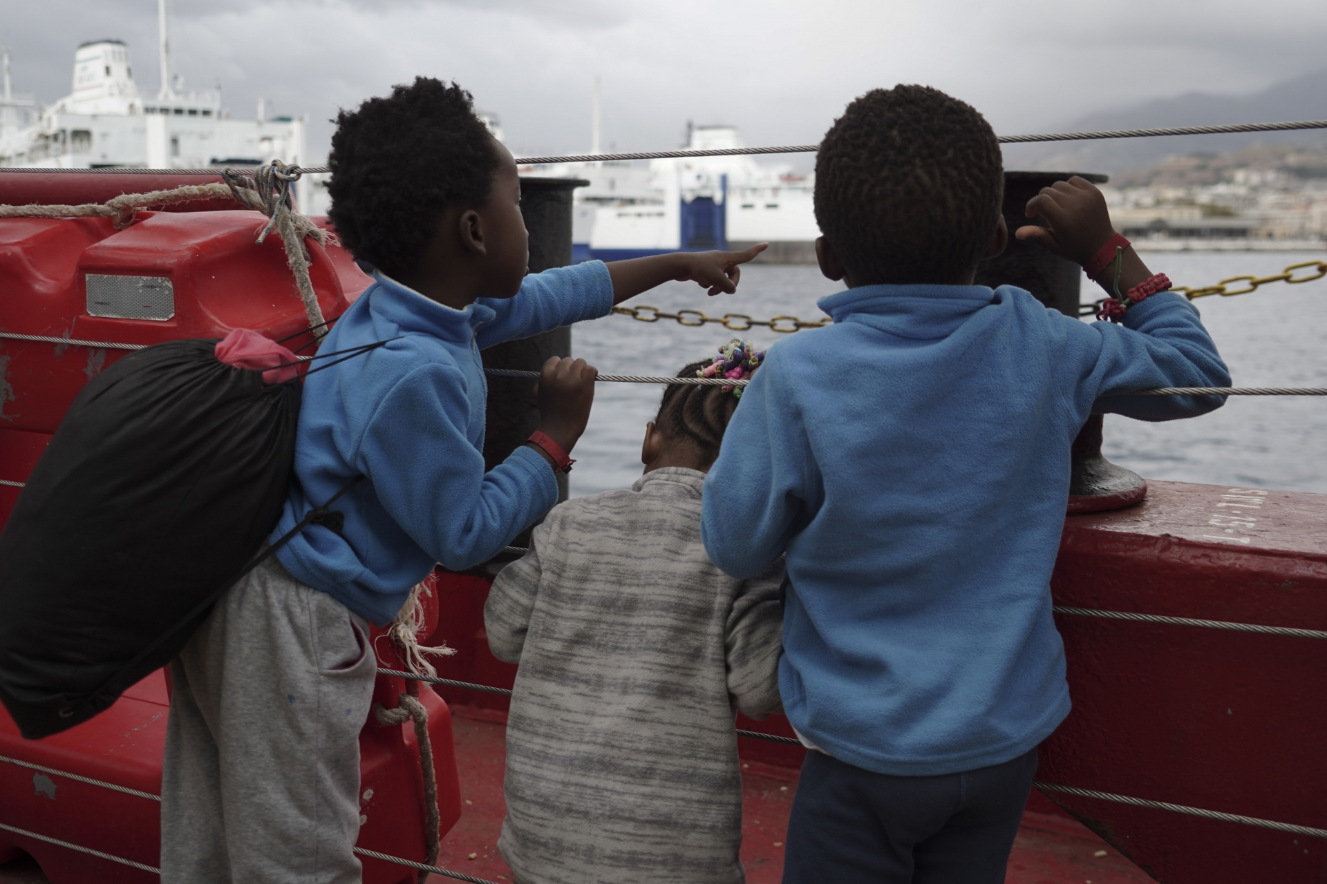 Children wave at a boat from aboard the Ocean Viking as it reaches the port of Messina, Italy