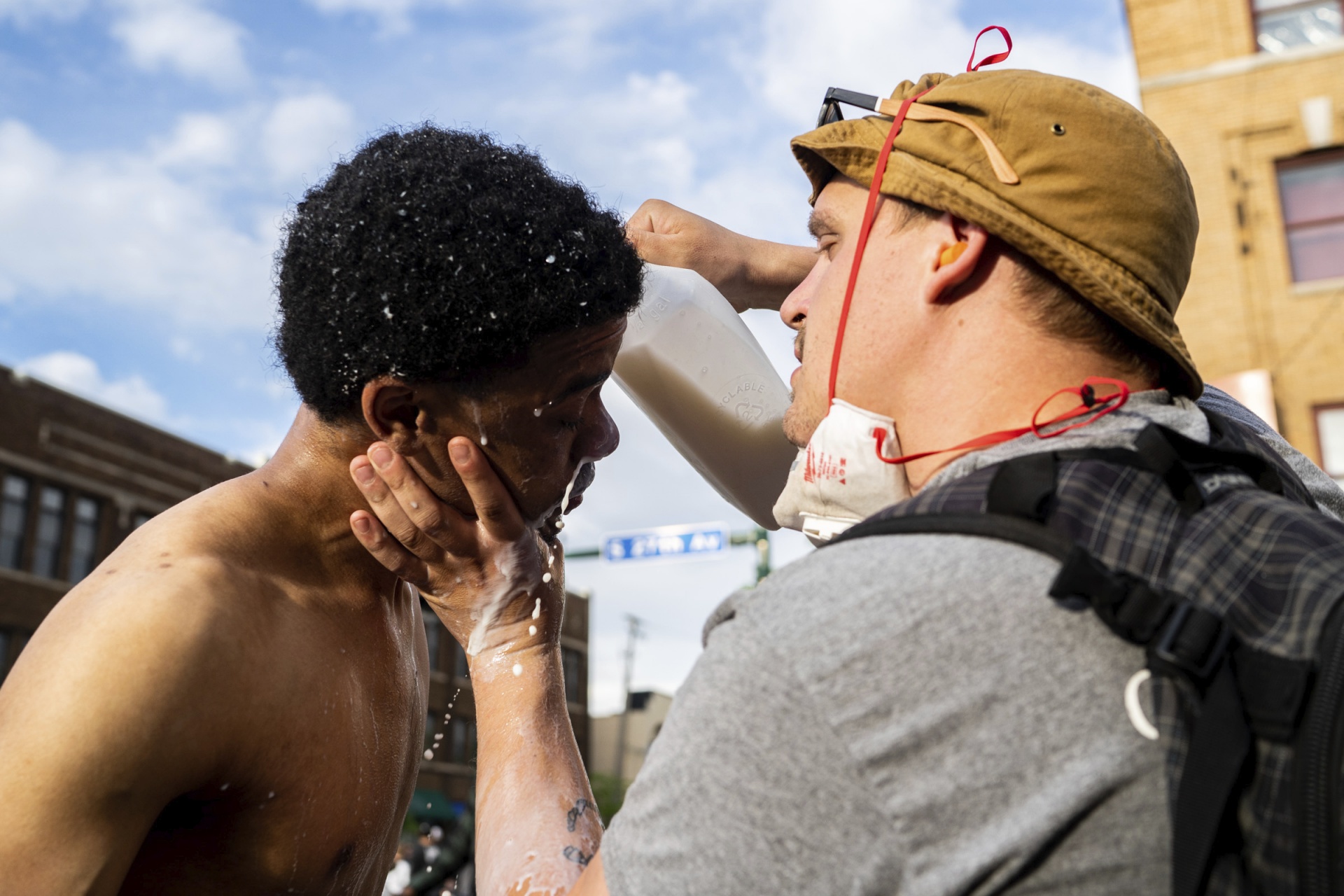 A man pours milk onto the face and eyes of another
