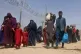 Afghans walk through a security barrier as they enter Pakist