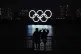A man and a woman look at the Olympic rings float in the wat