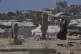 A displaced Palestinian woman carries a child as she walks past makeshift tents set up in a cemetery in Khan Younis, in the southern Gaza Strip, September 20, 2025