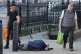 People walk past a homeless person asleep on the street beside the entrance to Westminster underground station and in the shadows of Big Ben and the Houses of Parliament in central London, July 19, 2024