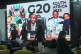 People walk by a large screen TV where South African President Cyril Ramaphosa holds a wooden gavel as he officially closes the G20 leaders' summit, in Johannesburg, South Africa, November 23, 2025