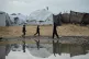 Displaced Palestinian children walk through a tent camp after stormy weather in Gaza City, December 10, 2025