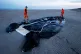 Town employees walk next to an inflatable boat punctured by French police and used by migrants to cross the Channel, Monday, Dec. 22, 2025 on the beach of Gravelines, northern France