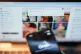 The Grok app on an iPhone, against the backdrop of search results displayed on the social media platform X (formerly Twitter) on a laptop