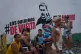 People sit near a mural of former President Nicolas Maduro with a message that reads in Spanish: ‘We want them back,’ during Carnival celebrations in Caracas, Venezuela, February 17, 2026