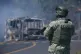 A soldier stands guard by a charred vehicle after it was set on fire in Cointzio, Michoacán state, Mexico, February 22, 2026