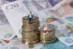 Models of a man and woman stand on a pile of coins and bank notes