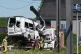 The remains of the minibus are moved to a flatbed truck
