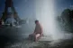 A person cools off at Trocadero fountain near the Eiffel Tower during a heat wave in Paris, Wednesday, June 24, 2026