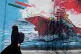 A woman walks past a mural depicting a U.S. aircraft carrier under missile attack in downtown Tehran, Iran, June 8, 2026