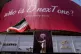 A man waves an Iranian flag beneath a billboard reading in English, 