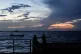 People sit on the seawall as the sun sets in Georgetown, Guyana, November 19, 2024