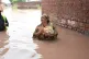A woman heads back to her home after receiving food provided by rescue workers at a flooded area near Lahore, Pakistan, June 27, 2026