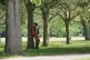 A worker stands in the shade under some trees in Greenwich Park, London