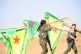 Women carry YPG and YPJ flags in Rojava
