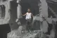Palestinians inspect the damage of destroyed buildings follo