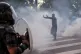 A protester tries to reason with police firing tear gas at c
