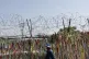 A visitor wearing a face mask walks in front of the wire fen