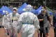 A policeman wearing a protective suit stands watch people li