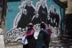 Women walk past a mural symbolizing death, on their way to t