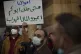 An anti-government protester holds an Arabic sign that reads