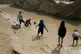 Children play in a mud puddle in the section for foreign fam