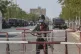 An armed police officer stands guard along a cordoned-off ro