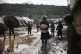 Syrian refugees walk through a camp for displaced people mud