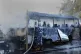 a Syrian firefighter extinguishes a burned bus at the site o