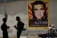 Pedestrians walk near a poster asking for the freedom of Col