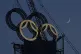 A worker labors to assemble the Olympic Rings onto of a towe
