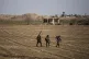 Syrian Democratic Forces fighters walk in a field in Hassake