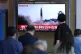 People watch a TV screen showing a news program reporting ab
