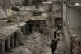 Women walk in a neighborhood heavily damaged by airstrikes i