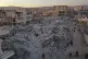 People walk past collapsed buildings following a devastating