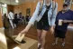 A man waits as a woman drops her ballot into a box at a poll