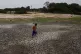 A little boy walks across a dry, cracked area of the Negro R