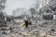 Palestinians walk by buildings destroyed in the Israeli bomb