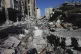 A Palestinian walks through destruction from the Israeli bom