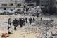 Palestinians walk through the destruction left by the Israel