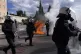Riots police stand in front of the Parliament as fires from 