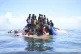 Rohingya refugees stand on their capsized boat before being 