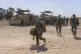 Israeli soldiers stand next to personnel carriers (APC) near