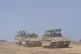 Israeli soldiers drive personnel carriers near the border wi