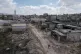 A man walks on a damaged road following an Israeli army raid