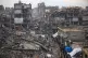 Palestinians walk in the destruction caused by the Israeli m